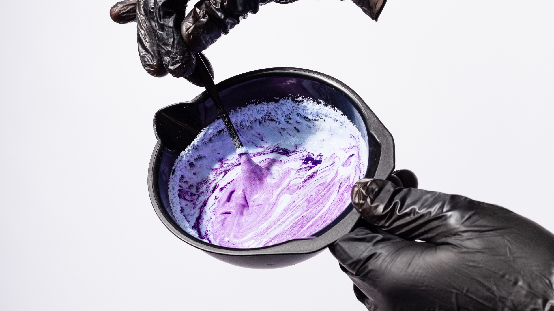 A person in black gloves holding a purple and black bowl