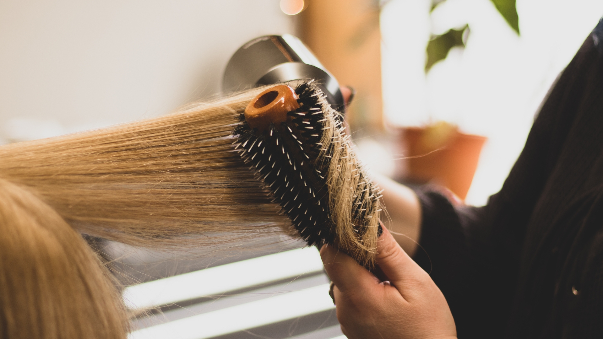 A woman blow drying her hair with a brush