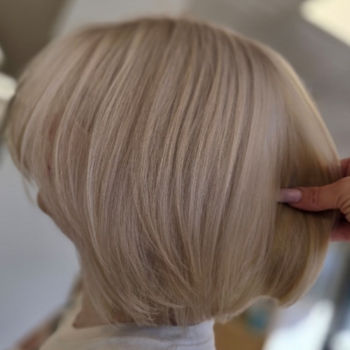 A woman is cutting her blonde hair with scissors