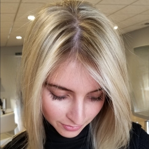 A woman with blonde hair is looking down at her cell phone